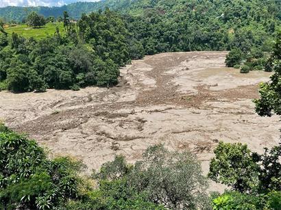 Eine schlammige Flutwelle reißt am 26. August 2026 nach Sturzfluten in Galchhi im nepalesischen Distrikt Dhading durch einen Fluss