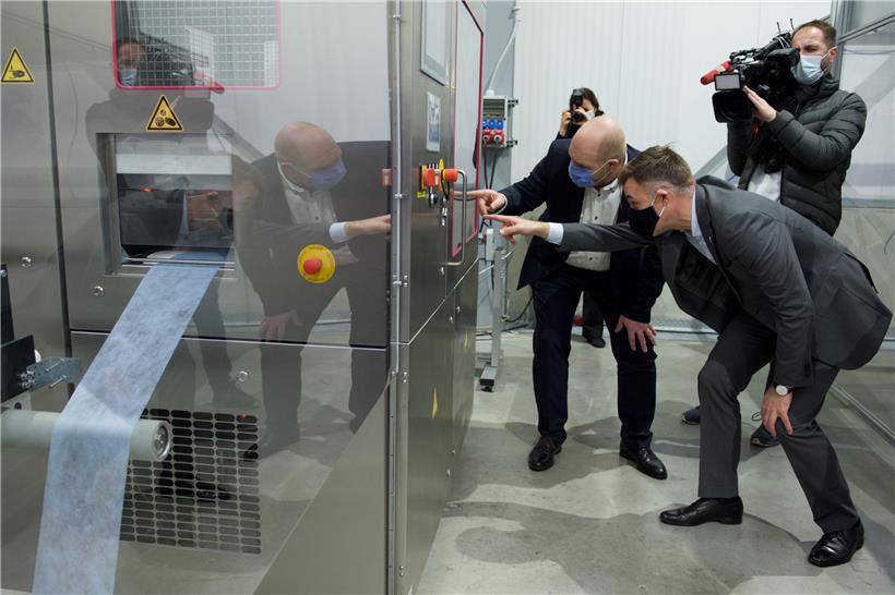 Einer der Wissenschaftler von MPG zeigt Wirtschaftsminister Fayot die neue Maschine zur Herstellung von Virus-abweisendem Material für Gesichtsmasken 
