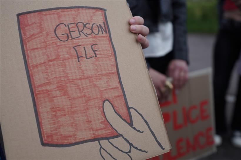 Eines der Protestplakate zeigt eine rote Karte mit den Worten „Gerson“ und „FLF“
