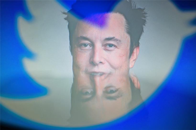 Elon Musk, CEO von Tesla und SpaceX, hinter den Silhouetten des Twitter-Logos
