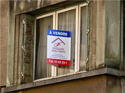 Schild mit Aufschrift „à vendre“ vor Haus, Symbol für Immobilienverkauf und Kaufangebote in Frankreich