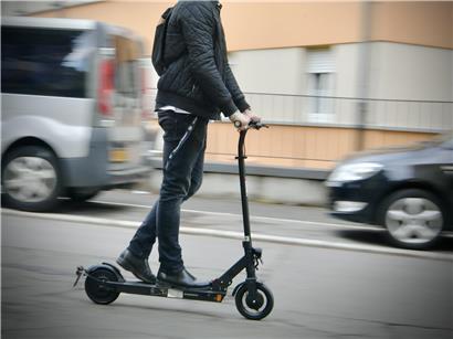 Unfall mit illegalem E-Scooter auf Straße, beschädigtes Fahrzeug und Unfallstelle sichtbar