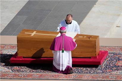 Erzbischof Diego Giovanni Ravelli, mit dem Rücken zur Kamera, kniet neben dem Sarg von Papst Franziskus auf dem Petersplatz im Vatikan
