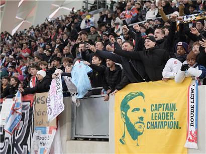 Junge Fußballfans jubeln im Stadion und unterstützen ihren Lieblingsverein begeistert bei einem Spiel.