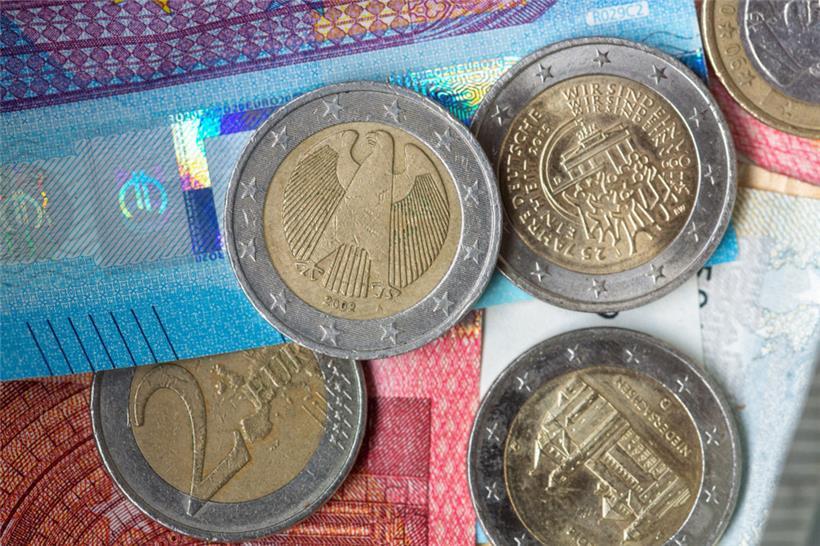 Euro-Münzen und Banknoten liegen aufeinander
