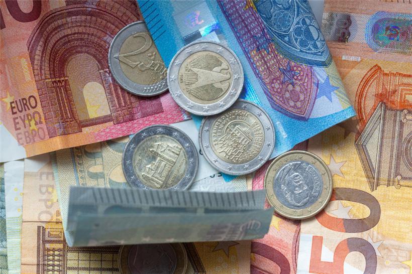 Euro-Münzen und Banknoten liegen aufeinander
