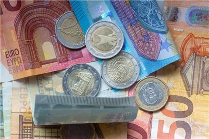 Euro-Münzen und Banknoten liegen aufeinander
