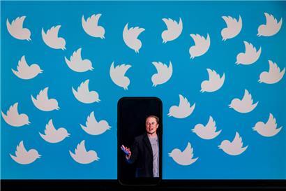 (FILES) This file illustration photo taken on August 5, 2022 shows a cellphone displaying a photo of Elon Musk placed on a computer monitor filled with Twitter logos in Washington, DC. – The New York Stock Exchange suspended trading of Twitter shares on October 4, 2022 following a Bloomberg report on a possible new takeover…
