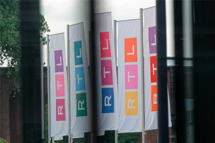 Fahnen des Fernsehsenders RTL stehen auf dem Platz vor dem Firmengebäude

