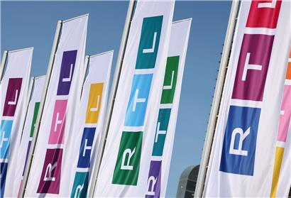 Fahnen mit dem neuen Logo des Fernsehsenders RTL. Die drei Buchstaben des Privatsenders sind schmaler, statt aus den drei Grundfarben Rot, Gelb, Blau sind die drei Blöcke des Logos aus allen möglichen Farben zusammengesetzt.
