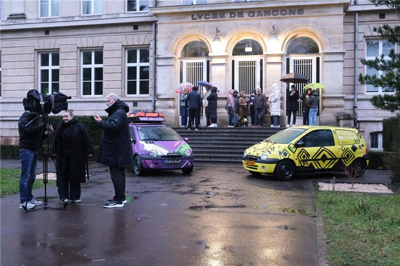 Familien und Freunde verabschieden Teams bei Abfahrt, machen Fotos und führen Gespräche am Startpunkt.