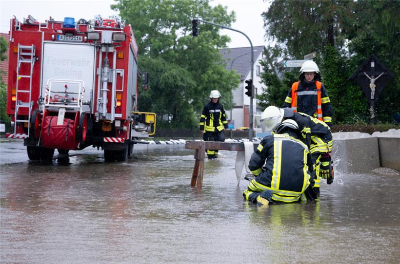 Feuerwehrleute bauen auf einer Straße eine Pumpe gegen das Hochwasser auf
