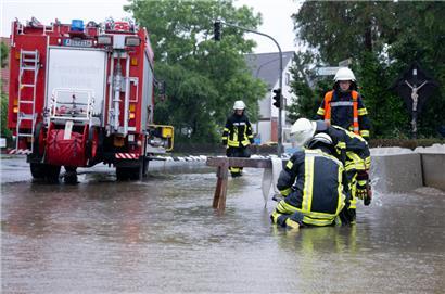 Feuerwehrleute bauen auf einer Straße eine Pumpe gegen das Hochwasser auf
