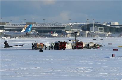 Feuerwehrleute des internationalen Flughafens Pearson arbeiten an einem auf dem Rücken liegenden Flugzeug der Delta Air Lines, das auf dem Weg von Minneapolis nach Toronto war, als es auf der Landebahn umstürzte
