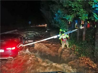 Feuerwehrleute hantieren mit einer Leiter an einem Auto, dass an der zu einem reißenden Strom angeschwollenen Pilach steht. Aufgrund der starken Niederschläge ist Sonntagfrüh ganz Niederösterreich zum Katastrophengebiet erklärt worden.

