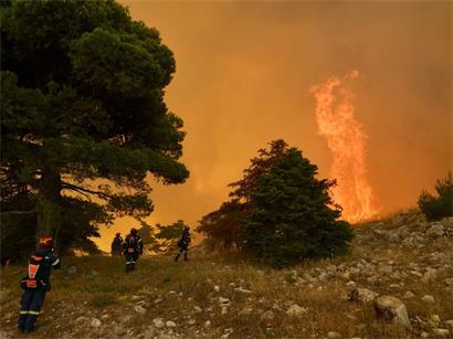 Feuerwehrleute nähern sich den hoch auflodernden Flammen auf dem Berg Kithairon in der Nähe von Porto Germeno, nordwestlich von Athen