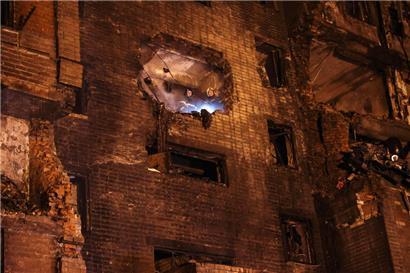 Feuerwehrleute schauen aus einem durch den Absturz des Militärflugzeugs teilweise zerstörten Wohnhaus
