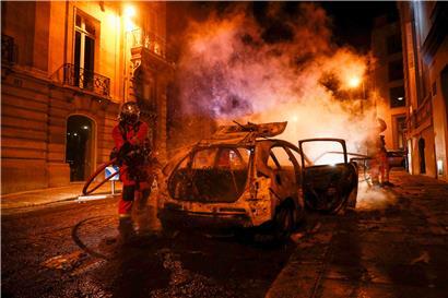 Feuerwehrmänner löschen in der Nacht zum Montag ein brennendes Auto in der Nähe der Champs-Elysées
