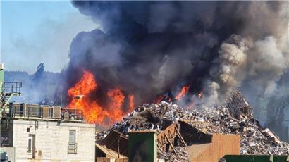 Flammen und Rauch schlagen aus einem Berg von Metallschrott im Trierer Industriehafen

