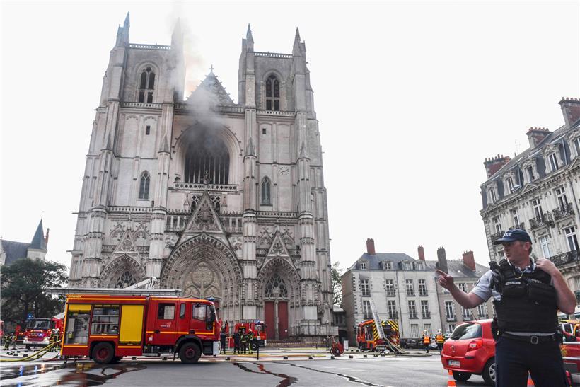 Frankreich, Nantes: Ein französischer Polizist gestikuliert vor der Kathedrale Saint-Pierre-et-Saint-Paul. In der Kathedrale der westfranzösischen Stadt Nantes ist ein Feuer ausgebrochen.

