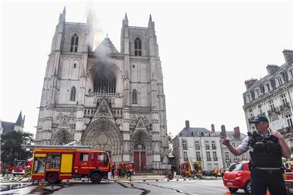 Frankreich, Nantes: Ein französischer Polizist gestikuliert vor der Kathedrale Saint-Pierre-et-Saint-Paul. In der Kathedrale der westfranzösischen Stadt Nantes ist ein Feuer ausgebrochen.
