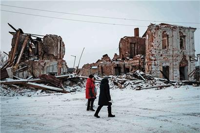 Frauen gehen an einem durch russischen Beschuss zerstörten Haus in Kupiansk, in der Region Charkiw, vorbei
