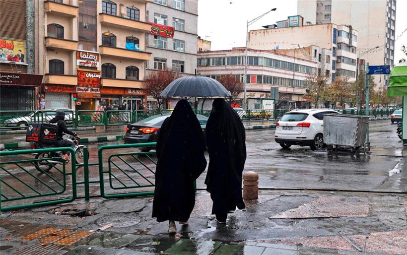 Frauen stehen am 5. Dezember auf dem Enghelab-Platz in der iranischen Hauptstadt Teheran unter einem Regenschirm
