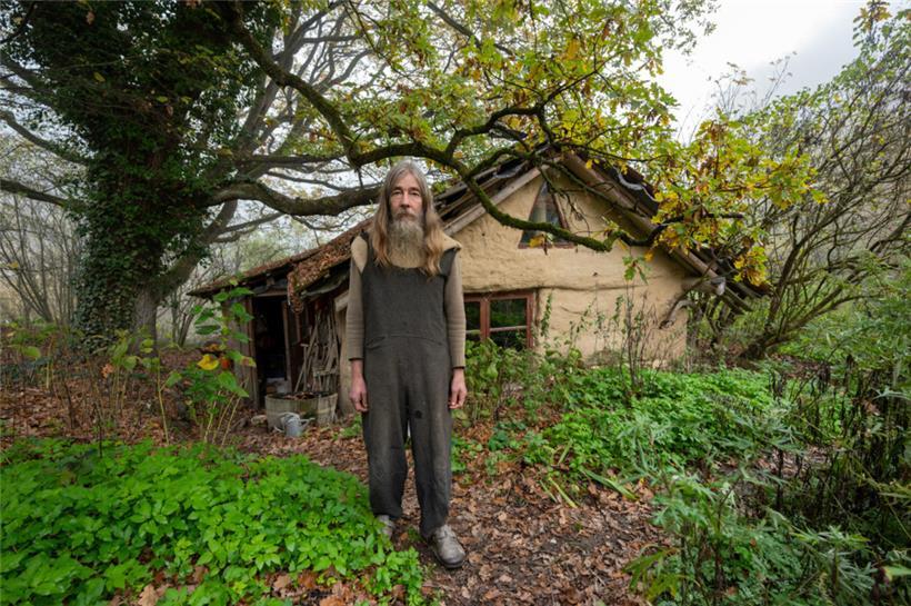 Friedmunt Sonnemann steht am frühen Morgen vor seinem Haus. Seit mehr als drei Jahrzehnten lebt er als Aussteiger in einer selbst gebauten Lehmhütte im Wald.
