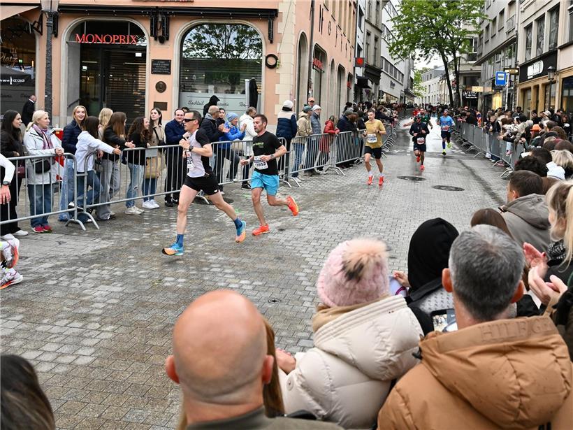 Läufer beim Marathon durch belebte Innenstadt mit jubelnden Zuschauern und festlicher Atmosphäre