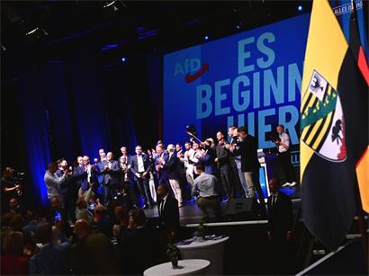 Funktionäre der AfD stehen bei der Wahlparty der AfD im Alten Theater vor dem Schriftzug „Es beginnt hier“ auf der Bühne