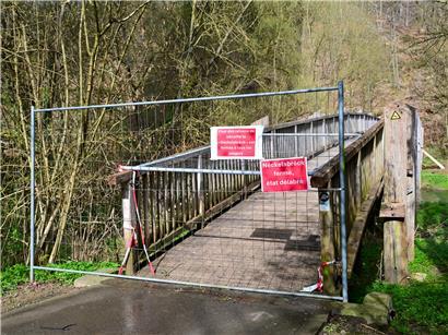 Fußgänger und Radfahrer stoppen überrascht auf halber Holzbrücke wegen Sperrung im Park