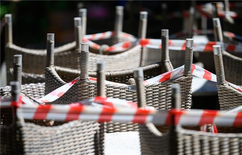 Gestapelte Stühle eines Restaurants sind mit Absperrband umgeben. Viele Unternehmer mussten wegen der Corona-Krise starke Verluste hinnehmen. 
