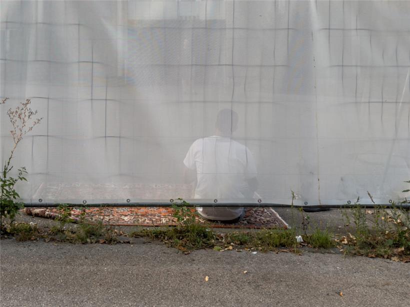 Getrübter Blick durch die Plane, die Asylsuchende und -begünstigte von der Gesamtgesellschaft trennt
