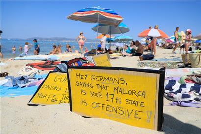 „Hallo Deutsche, zu sagen, dass Mallorca euer 17. Bundesland ist, ist beleidigend“, steht auf einem Schild, das an einem Strand auf Mallorca aus Protest gegen den Massentourismus auf der Balearen-Insel gezeigt wird
