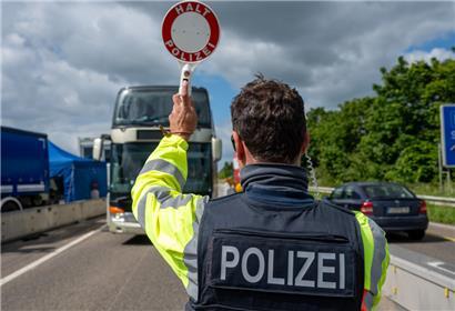 Halt, Polizei: Ein Bundespolizist stoppt während einer Grenzkontrolle im Sommer einen Bus auf der Trier-Autobahn
