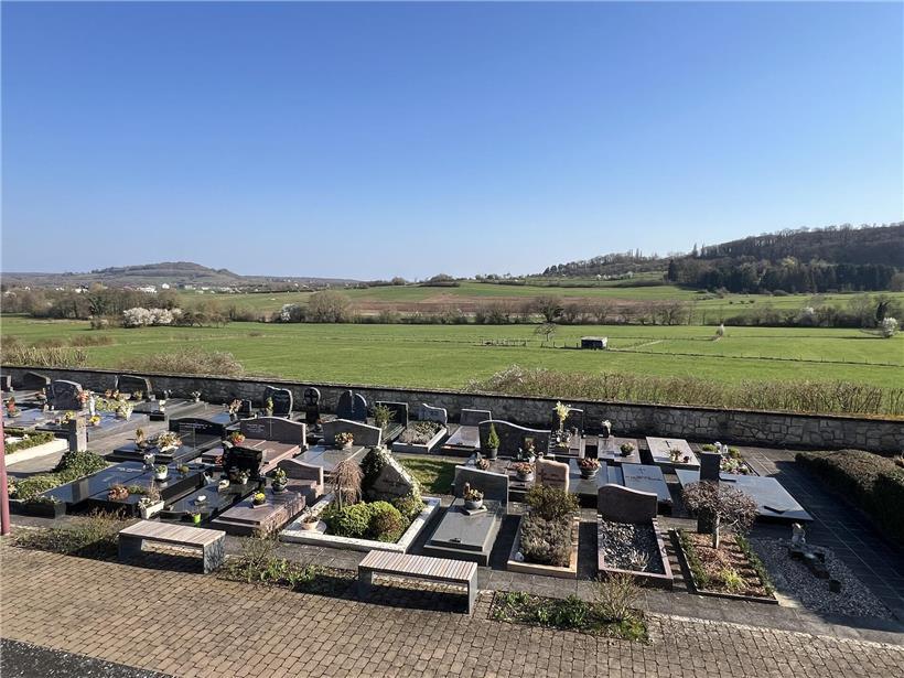 Bau der Unterkünfte hinter dem Friedhof in grünem Umfeld mit Baustellenfahrzeugen und Baugerüst