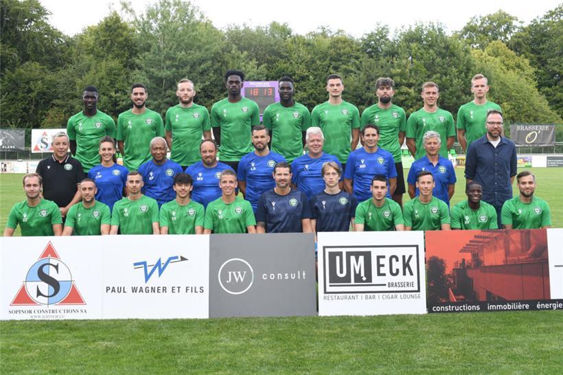 Hintere Reihe von links: Jean-Désiré Tibor (mittlerweile UNA Strassen), Halim Meddour (hat den Verein verlassen), Deniz Muric, Gédéon Tshiabuiye, Sékou Coulibaly, Kevin Agovic, Allan Grun, Noah Dédénon, Thomas Selensky Mittlere Reihe von links: Jacques Wolter (Präsident), Christina Merten (Physio), Eiseu Pereira (Betreuer), Michel Stoll (Co-Trainer), Lars Schäfer (Trainer), Carlo Trierweiler (Co-Trainer), Mouloud Beltitane (Torwarttrainer), Claude…
