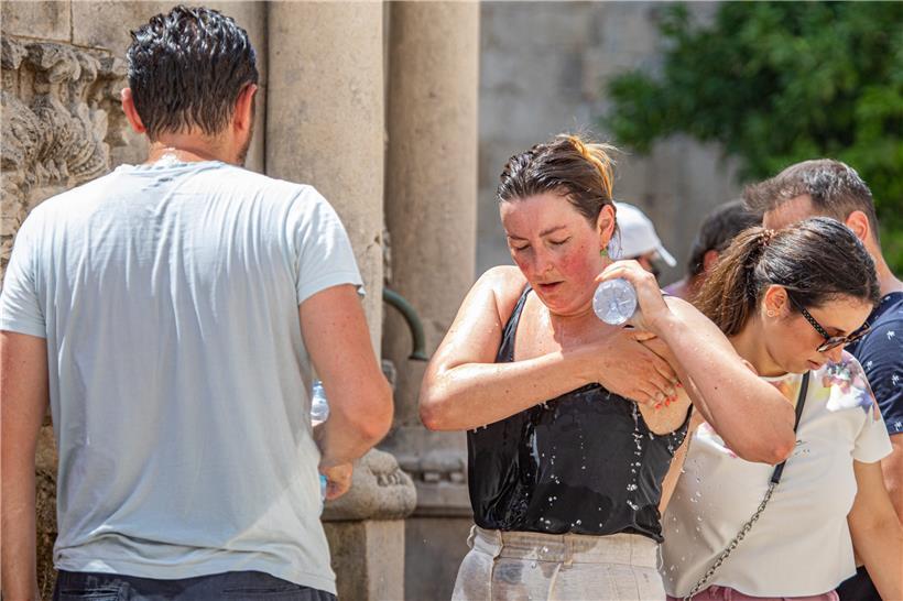 Hitzewelle an der Adria: Eine Touristin kühlt sich in der Altstadt von Dubrovnik an einem Springbrunnen ab
