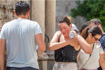 Hitzewelle an der Adria: Eine Touristin kühlt sich in der Altstadt von Dubrovnik an einem Springbrunnen ab
