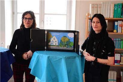 Illustratorin Claudine Furlano und Bibliotheksleiterin Tamara Sondag zeigen stolz das Cover des Kinderbuches
