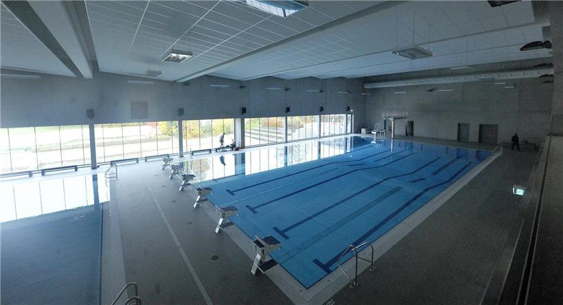 Leeres Hallenbad in Düdelingen mit stiller, blauer Wasseroberfläche und leeren Schwimmbahnen