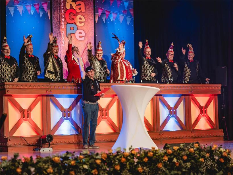 Guy Brecht im KaPeGe-T-Shirt und Kappe, lächelnd mit weniger Haaren, humorvoll verkleidet bei Eventauftritt