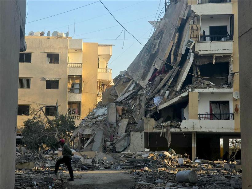 Anwohner in Beirut geht nachts nach israelischem Luftangriff an zerstörtem Gebäude im Libanon vorbei