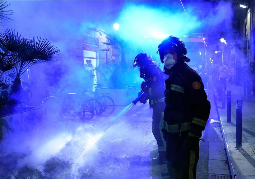 In Barcelona löschen Feuerwehrleute einen Brand nach einer Demo gegen die Corona-Maßnahmen
