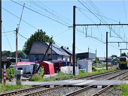 Zug und Schulbus kollidieren bei Unfall in Belgien, Unfallstelle mit Einsatzkräften und beschädigten Fahrzeugen