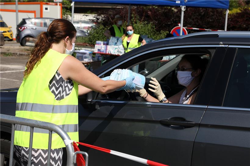 In Niederkorn überreicht eine Helferin Pakete mit Masken an eine Anwohnerin (Archivfoto)
