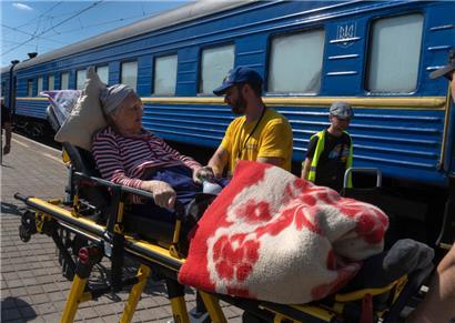 In Pokrowsk in der Ukraine helfen Freiwillige einer älteren Frau, die aus dem Kriegsgebiet evakuiert wurde
