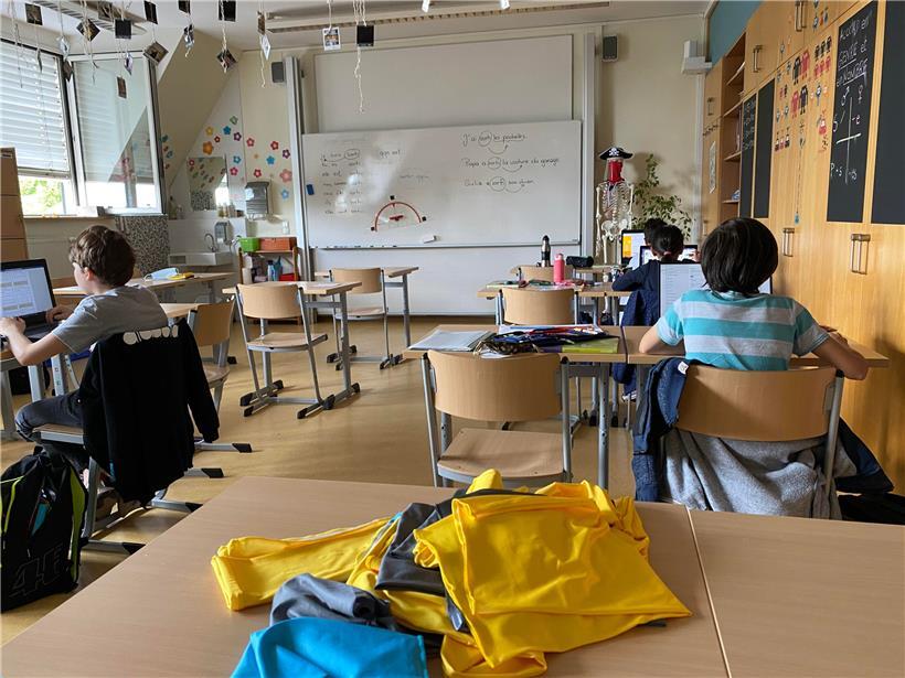 In der 5. Klasse in Beles-Post lernen die Schüler auf Laptops. Im Vordergrund liegen die bunten Buffs, die an die Kinder verteilt werden. 
