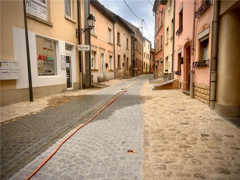 Abgeschlossene Straßenbauarbeiten am Straßenanfang mit frischem Asphalt und Bauzäunen im Hintergrund
