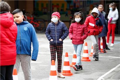 In einer Grundschule im französischen Elsass stehen Schulkinder mit und ohne Mundschutz Schlange im Pausenhof
